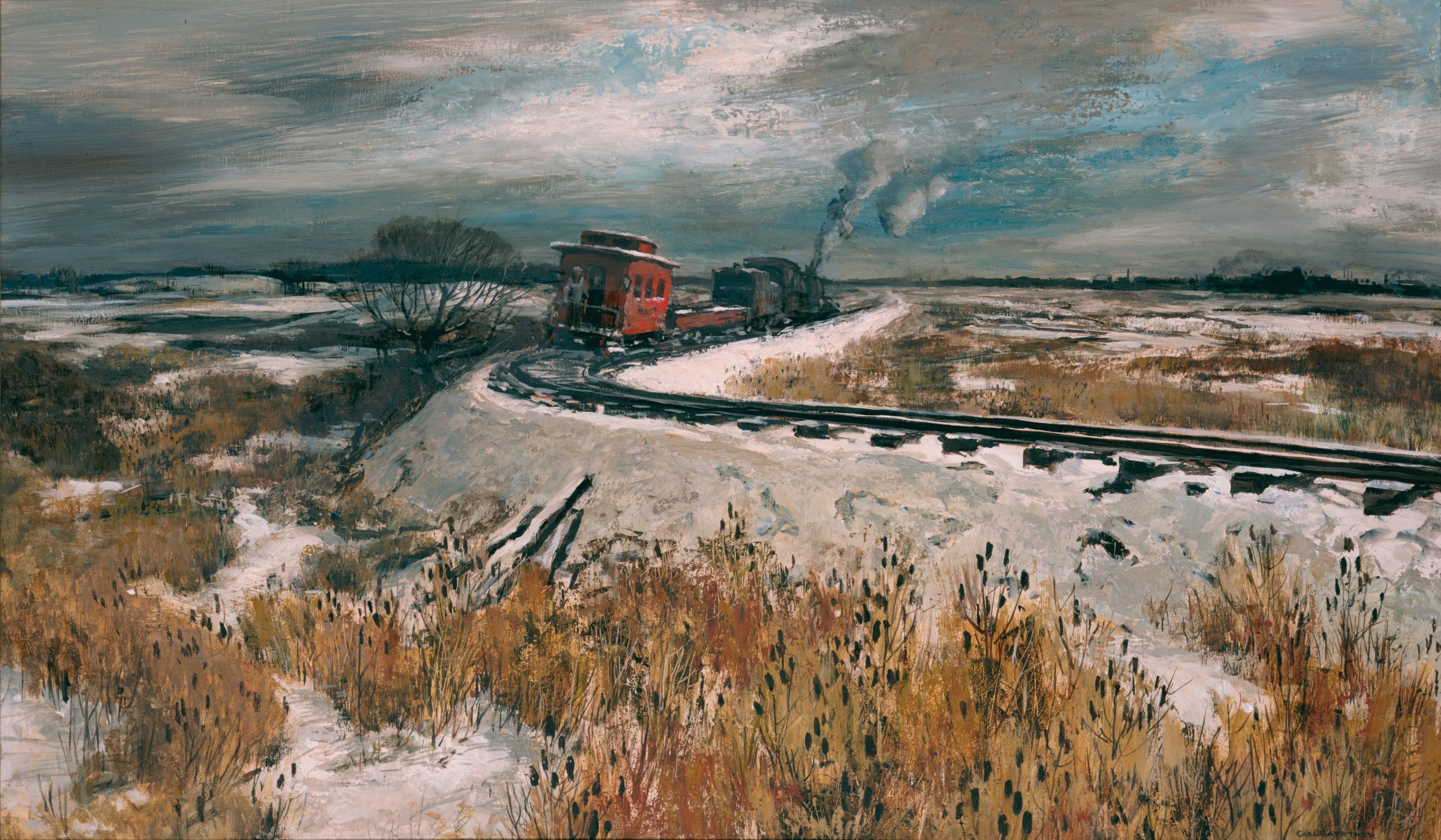 A freight train with red carriages travels through a snowy, rural landscape. Smoke billows from the locomotive against a cloudy sky. Bare trees and dry grasses line the tracks, creating a winter scene.